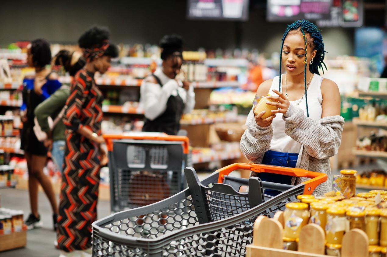 Frau überprüft im Supermarkt ein Honigglas auf Qualität – Entscheidungshilfe beim Manuka Honig kaufen