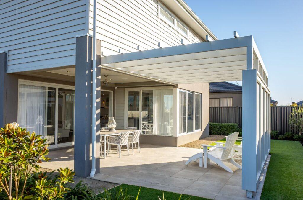 Moderne Terrassenueberdachung aus Aluminium am Neubau mit Essgruppe und Sonnenliegen – klarer Uebergang zwischen Haus und Garten
